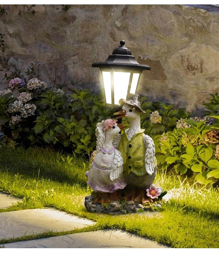 Decorative garden light with bird figures on a stone pathway.