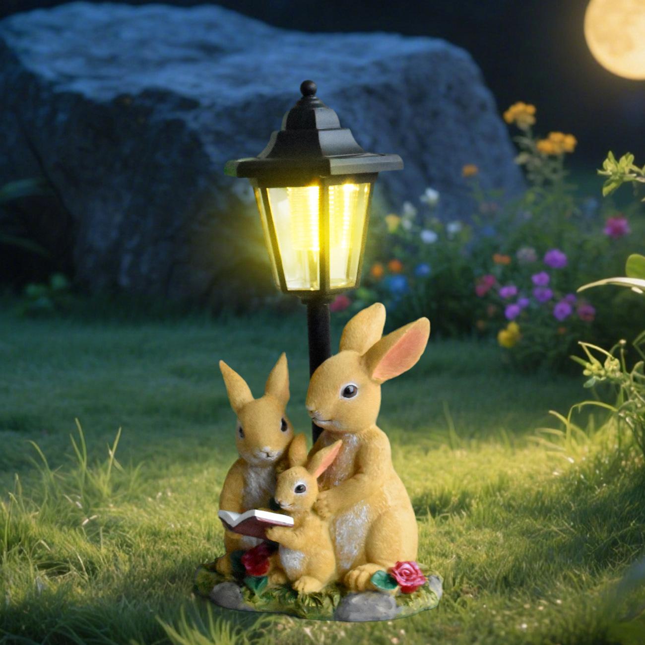 Decorative garden light with rabbit family under a lamp post at night.