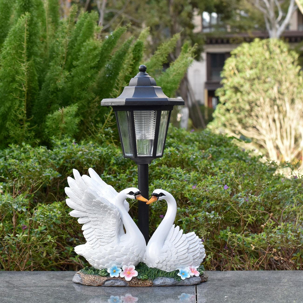 Solar lamp with swan statues on a garden path