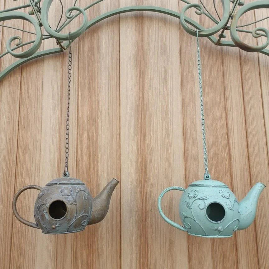 Two hanging teapot-shaped bird feeders on a wooden background