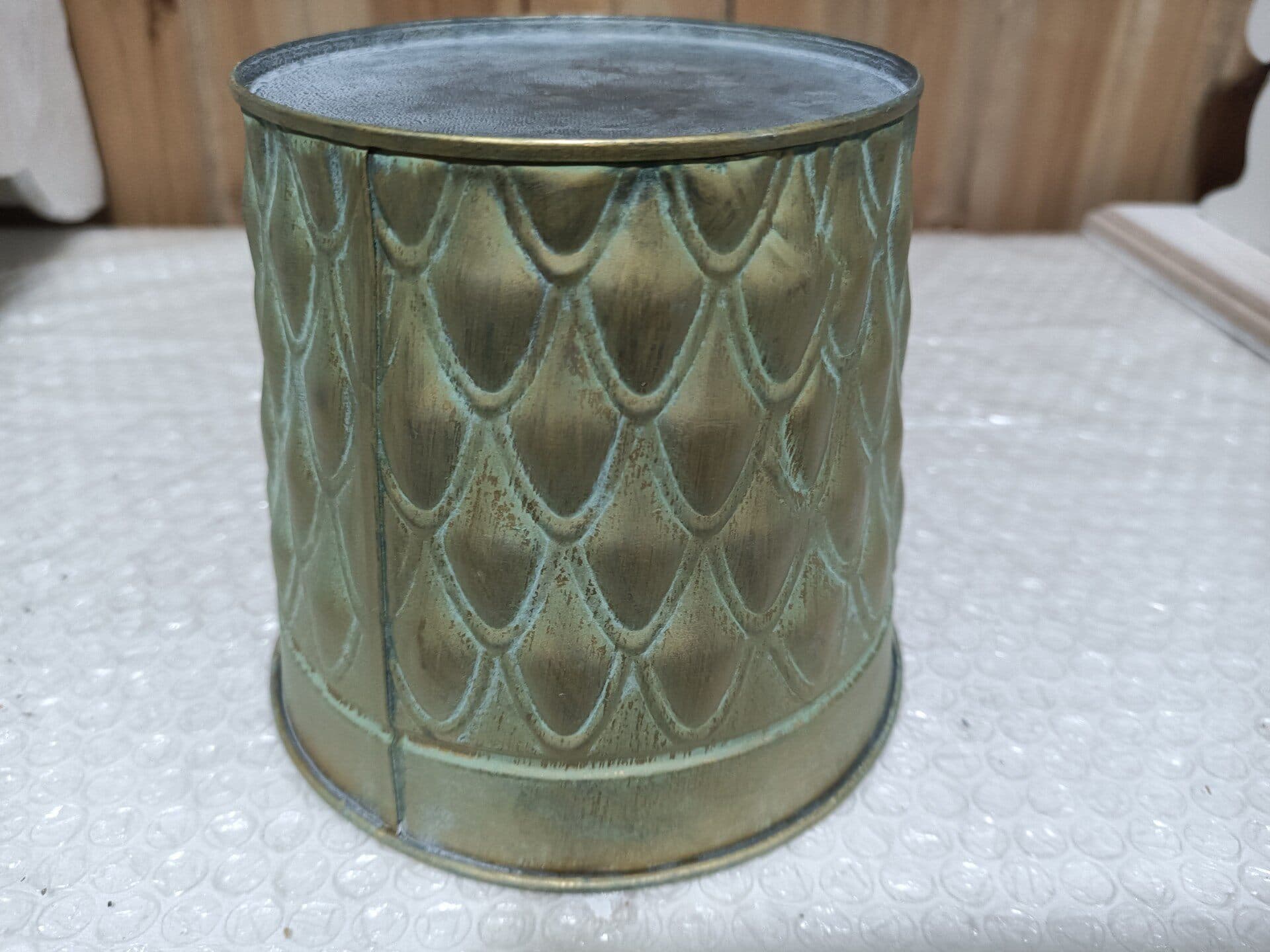 Green textured metal canister on a white surface