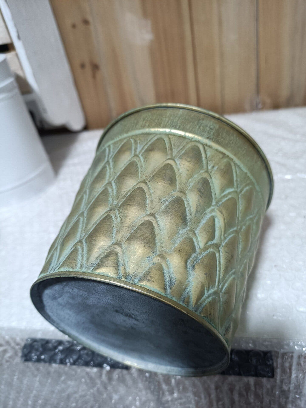 Decorative metal container with textured surface on a white surface