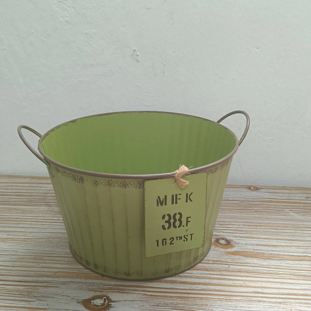Green metal bucket with handles on a wooden surface