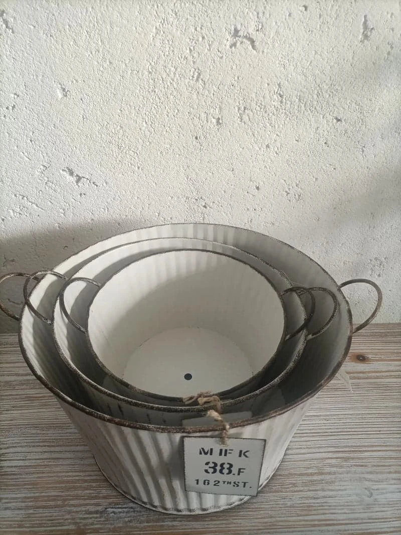 Set of three metal planters with a label on a textured surface