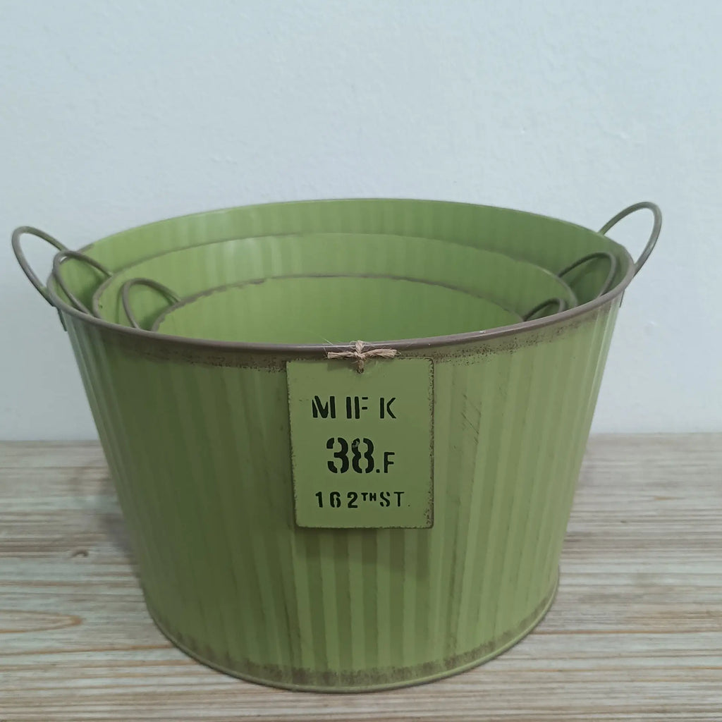 Green metal bucket with a label on a wooden surface