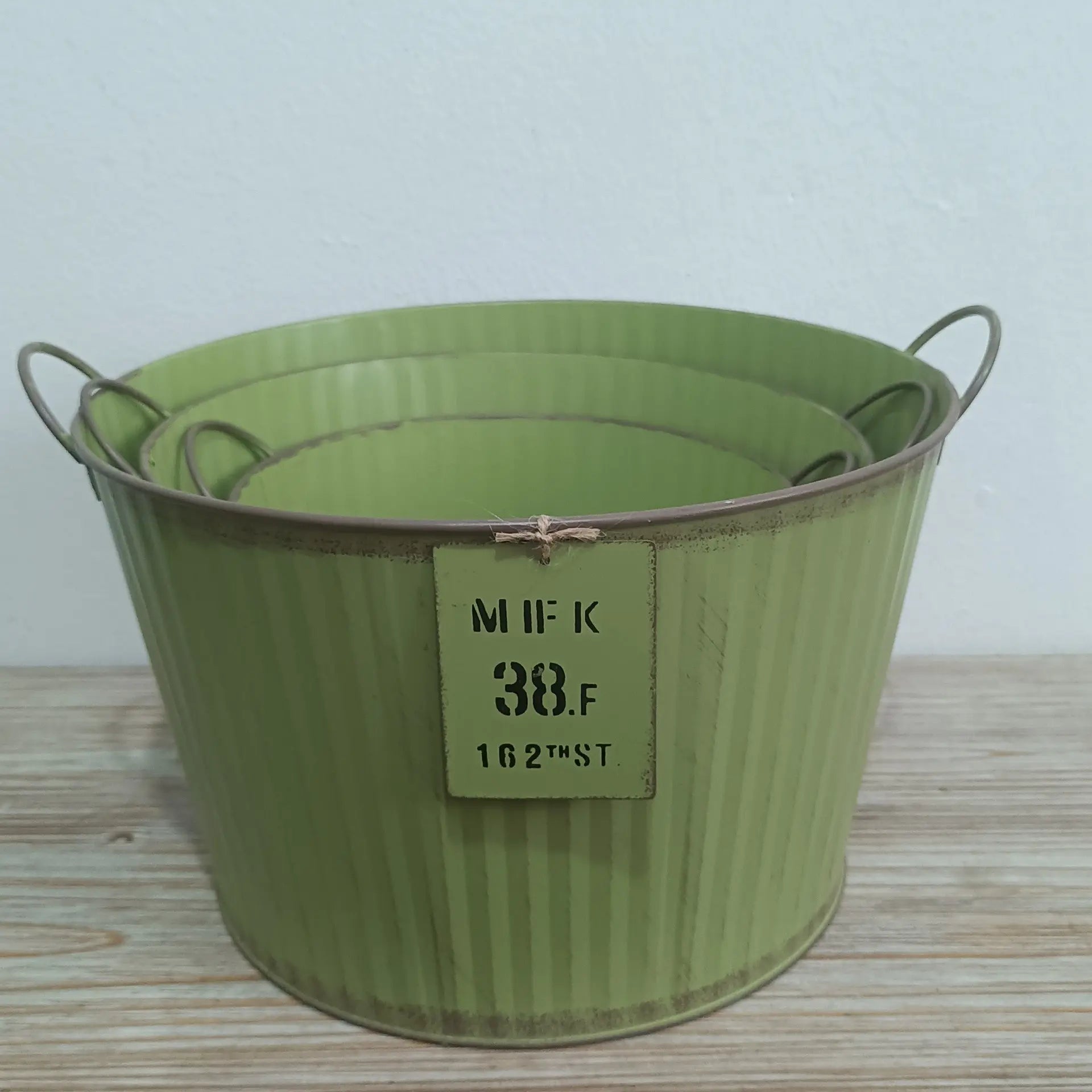 Green metal bucket with a label on a wooden surface