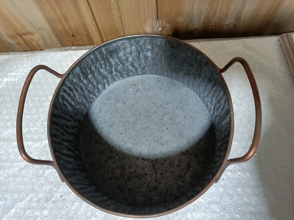 Decorative metal bowl with handles on a light-colored surface