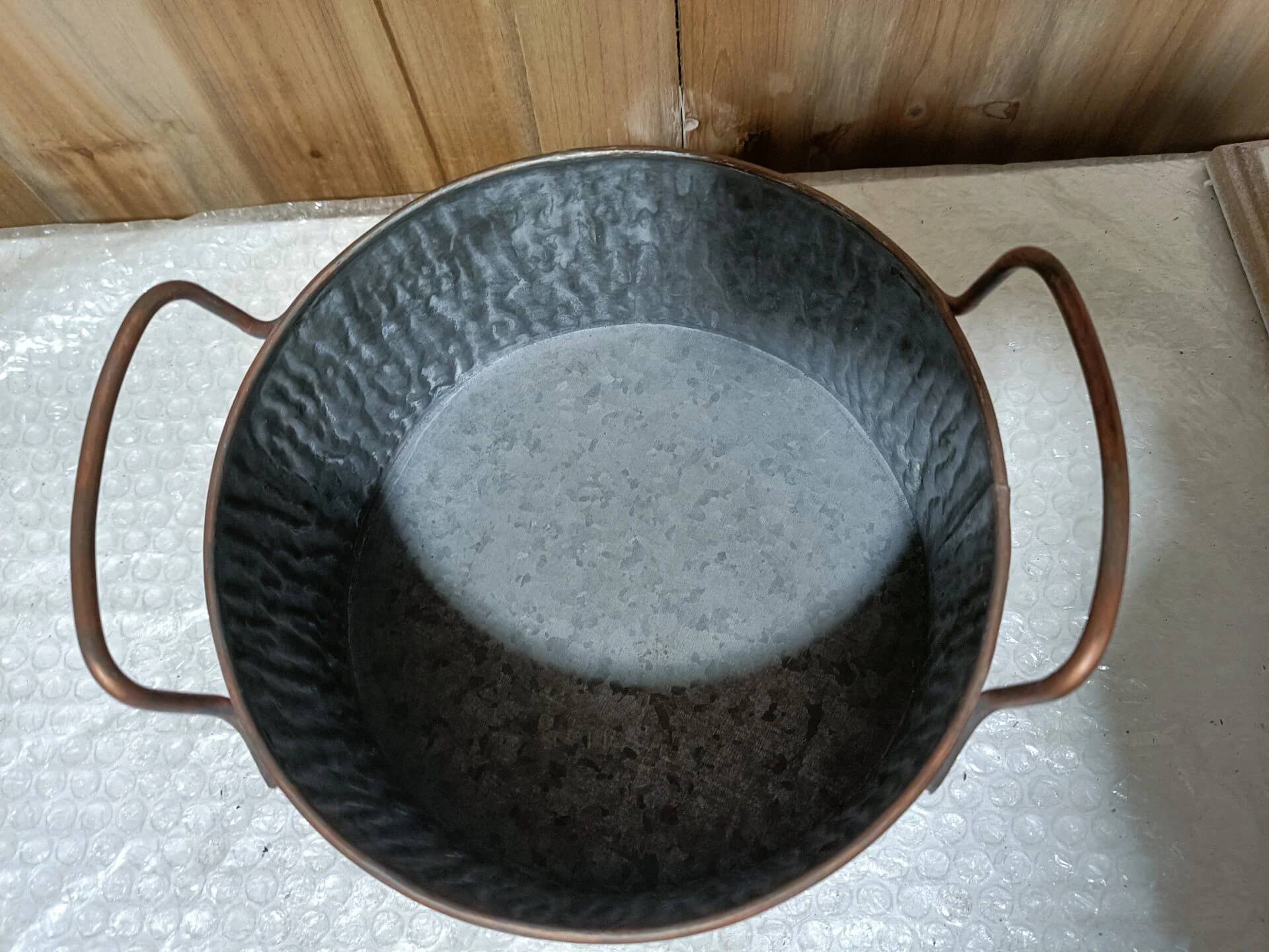 Decorative metal bowl with handles on a light-colored surface