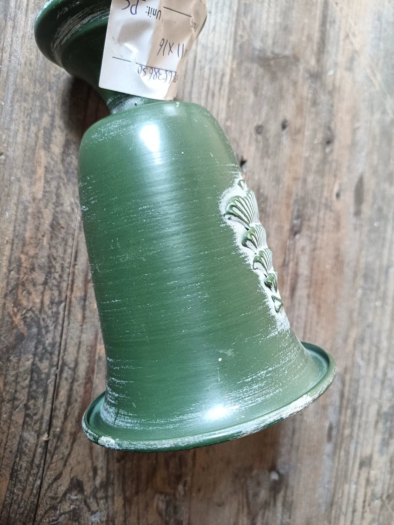 Green ceramic pot with a label on a wooden surface