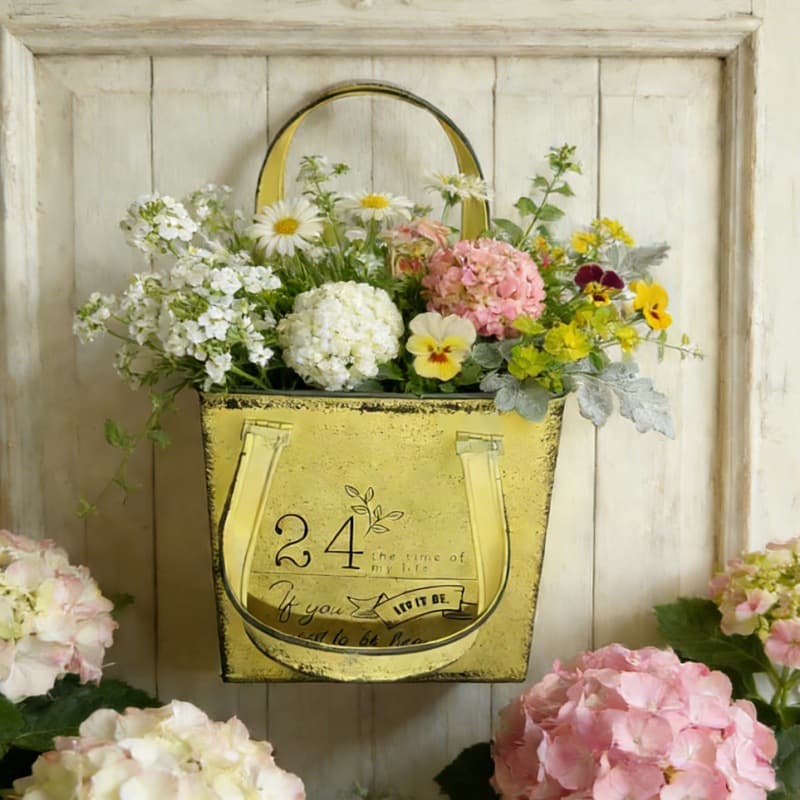 Decorative gold planter with flowers against a wooden wall