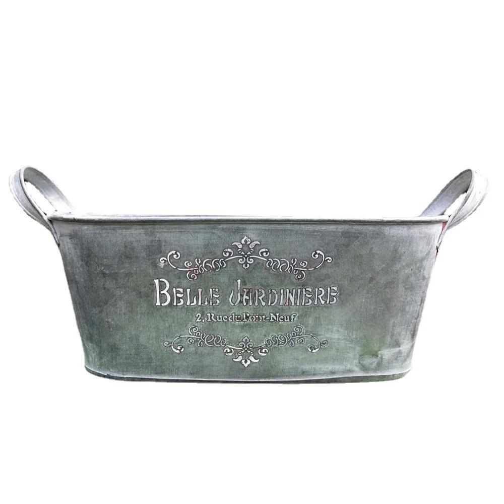 Metal basin with 'Belle Jardinière' text and floral designs on a white background