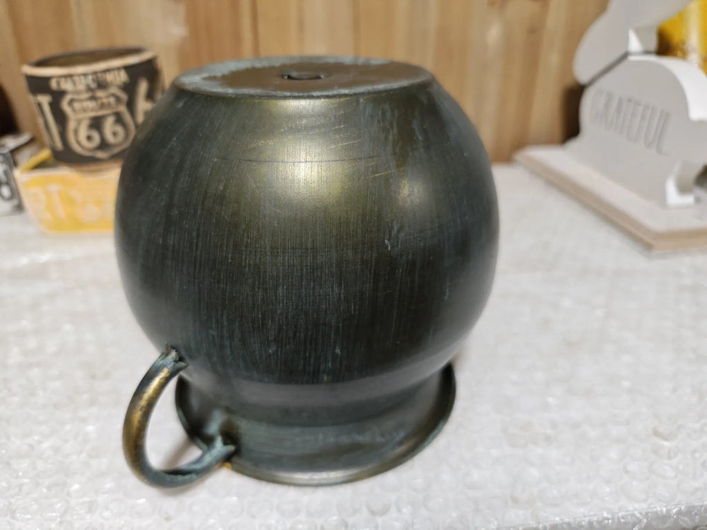 Dark bronze metal planter pot with one curved side handle, rounded bucket shape