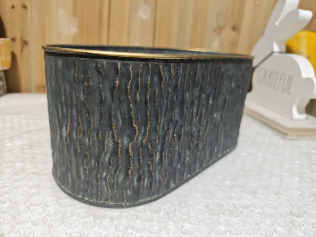 Dark faux-bark oval metal planter with gold-edged rim