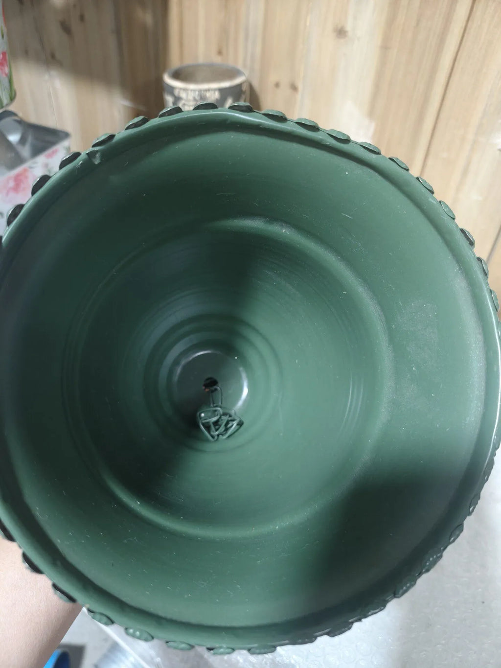 Green iron hanging bell underside close-up with riveted beaded trim