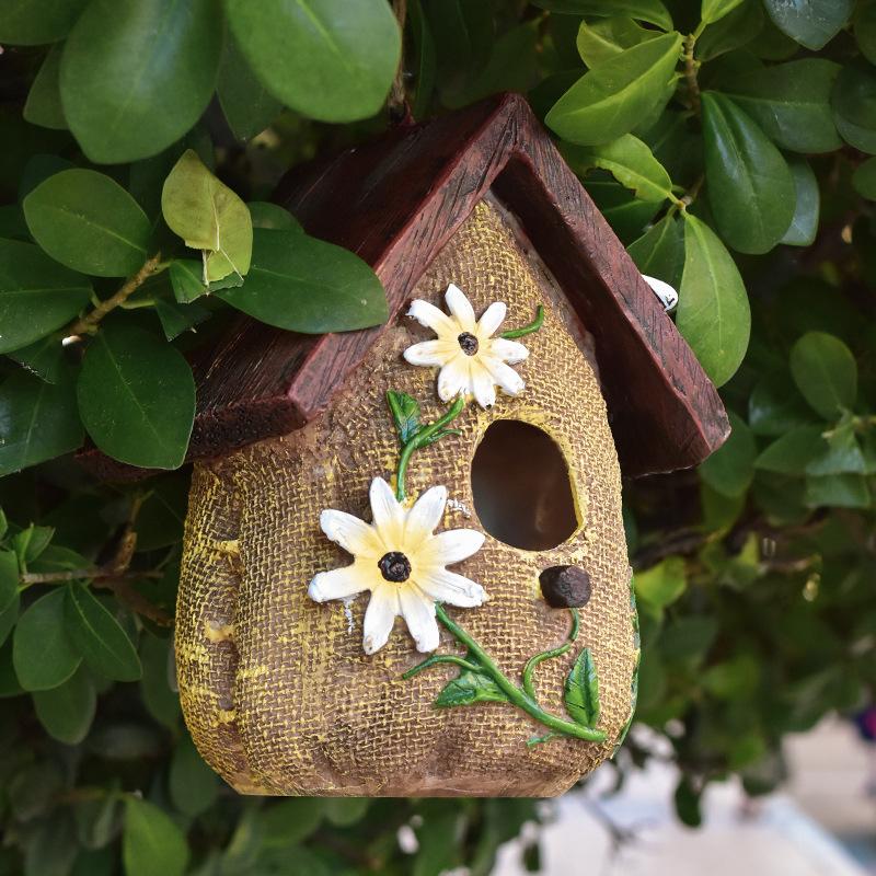 Hanging birdhouse ornament with burlap texture, white flowers, and green vine details