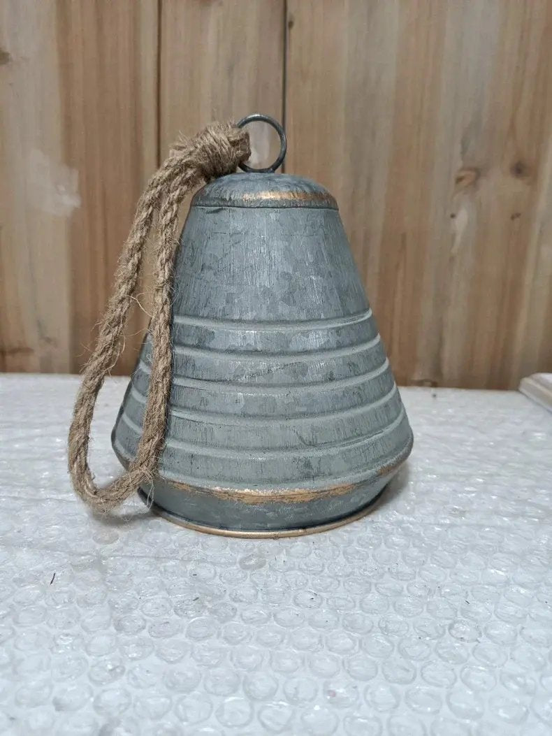 Weathered gray iron bell with rope loop handle, wide fluted body