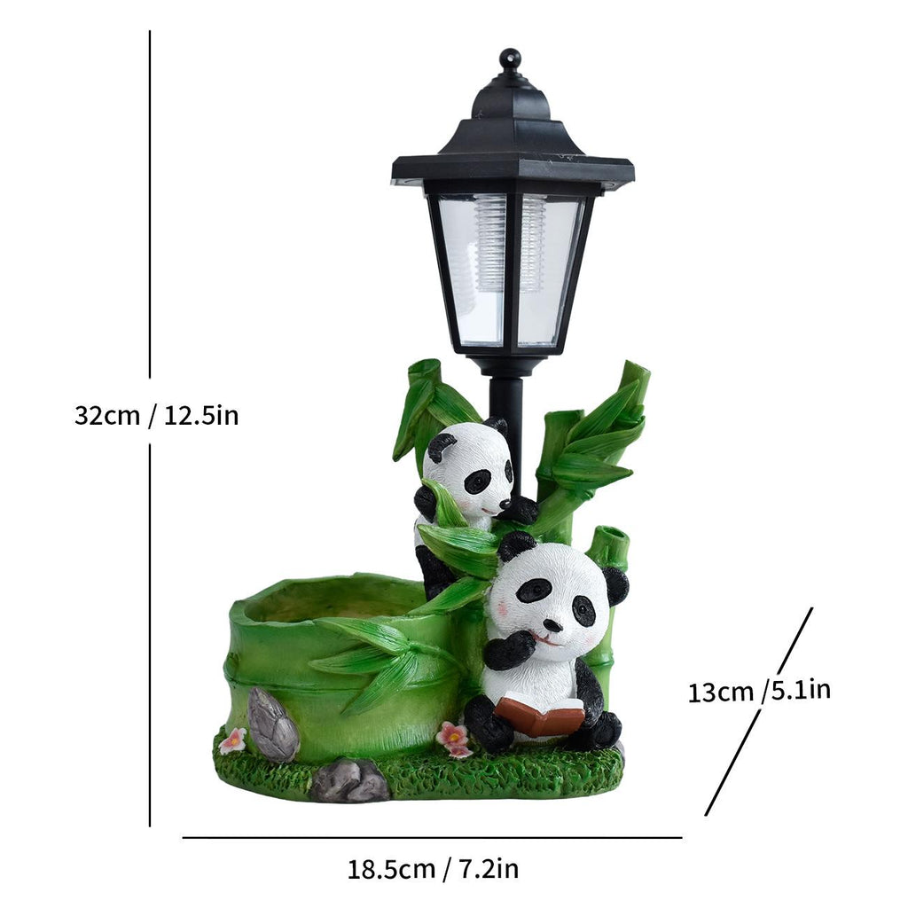 Solar garden animal statue with black lantern and two pandas hugging beside green leaves.