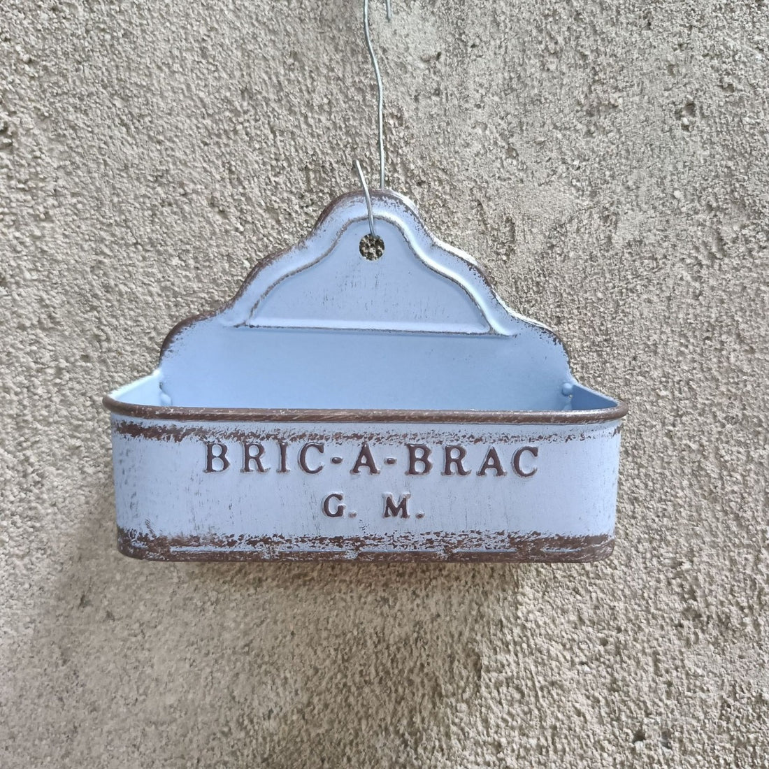Blue metal wall planter with “BRIC-A-BRAC G.M.” text and hanging loop.