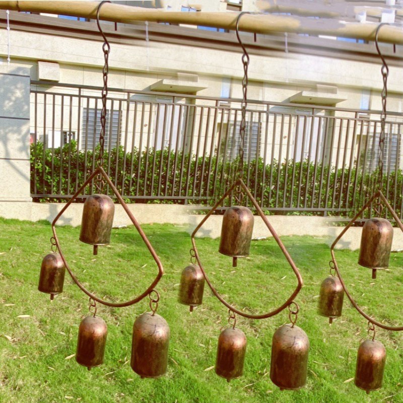 Campana de viento geométrica de bronce con forma de abanico y múltiples campanillas colgantes.