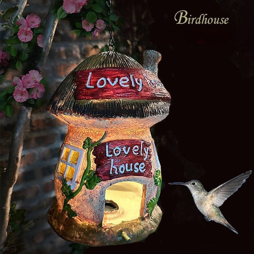Solar birdhouse lantern with red thatched roof, green vine accents, and warm glowing doorway