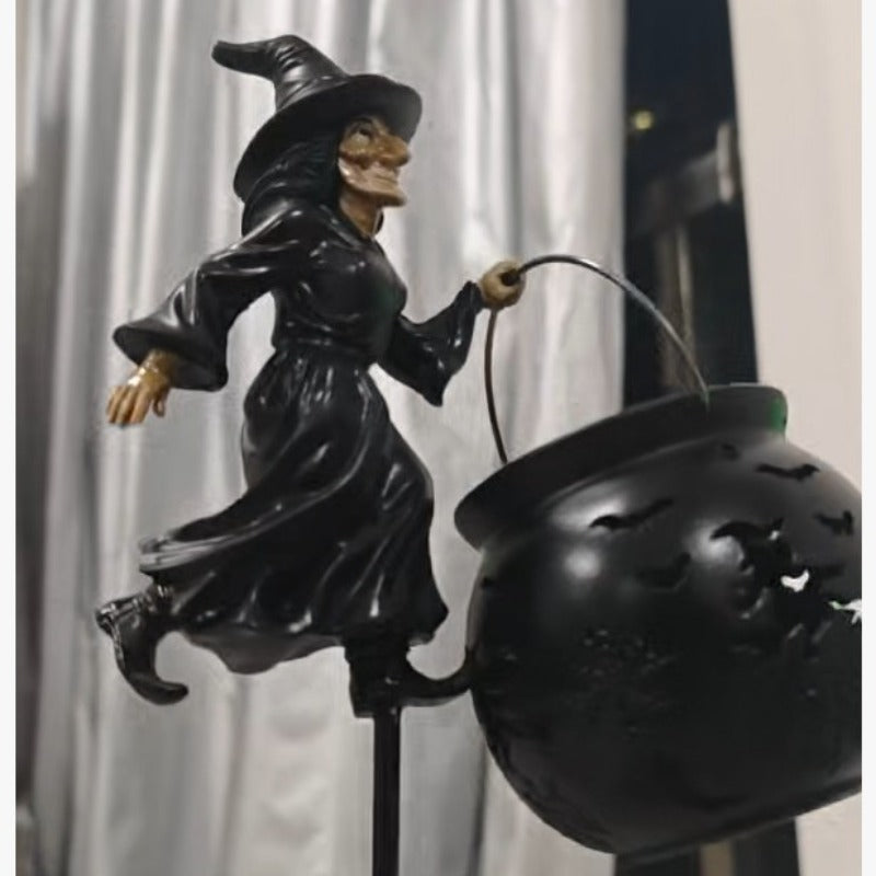 Halloween häxa påle trädgårdsljus, svart häxa som håller handtaget över glödande kittel
