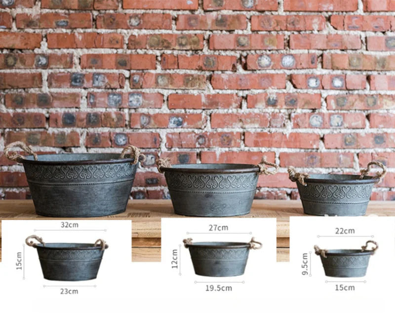 Three metal planters of different sizes against a brick wall with measurements displayed.