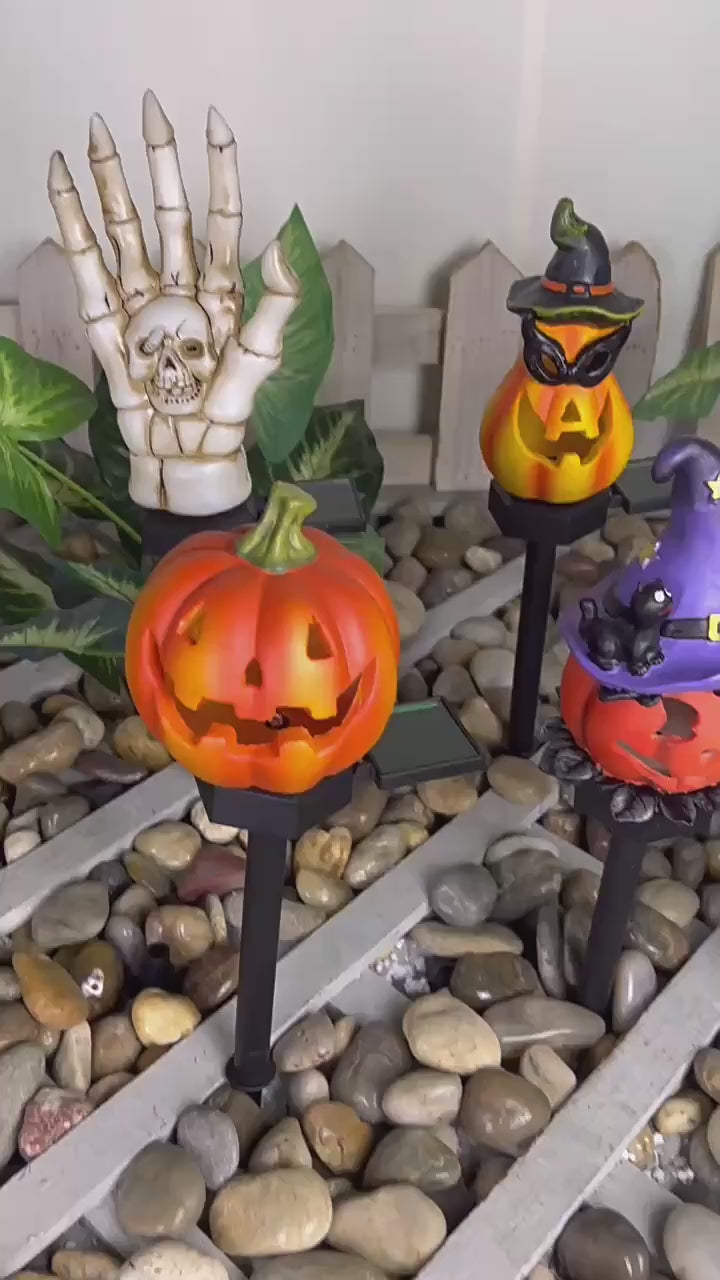 Video showing solar Halloween pathway lights including glowing pumpkins, skeleton hand, and witch hats along a garden path