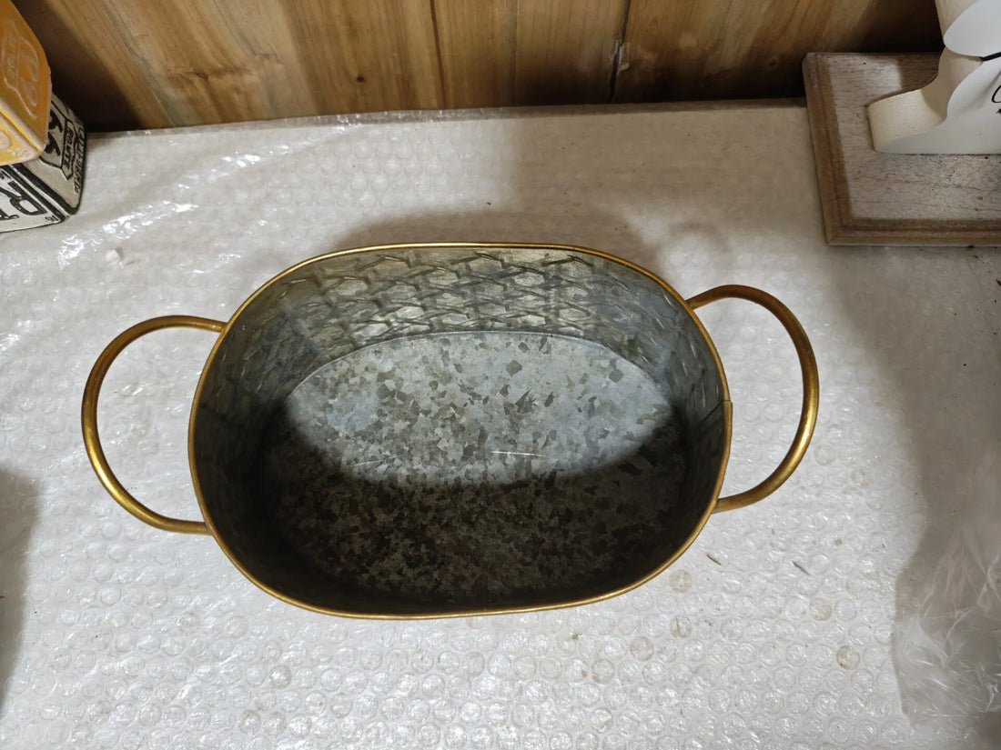 Oval metal planter tub with distressed gray interior and gold-toned side handles