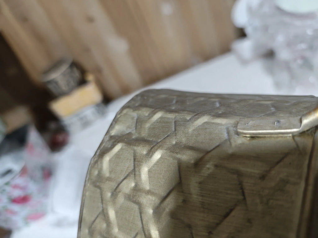 Close-up of embossed metal planter tub with gold-toned raised diamond texture