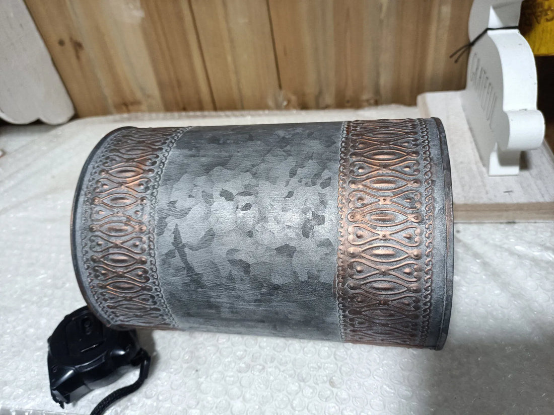 Cylindrical gray metal bucket with embossed sides and matching lid, rustic iron texture